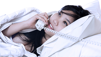 pretty asian girl on the phone in bed